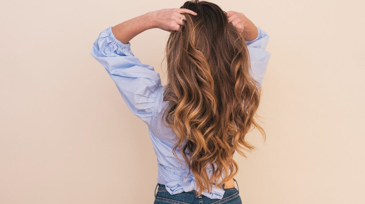 Woman combing her hands through her long light brown hair