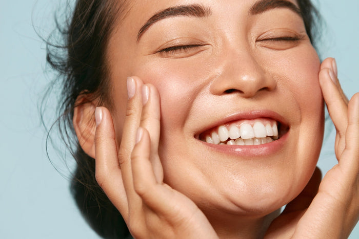 A lady closing her eyes with her hands on her cheeks