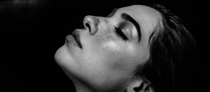 A woman tilts her face upwards and closes her eyes