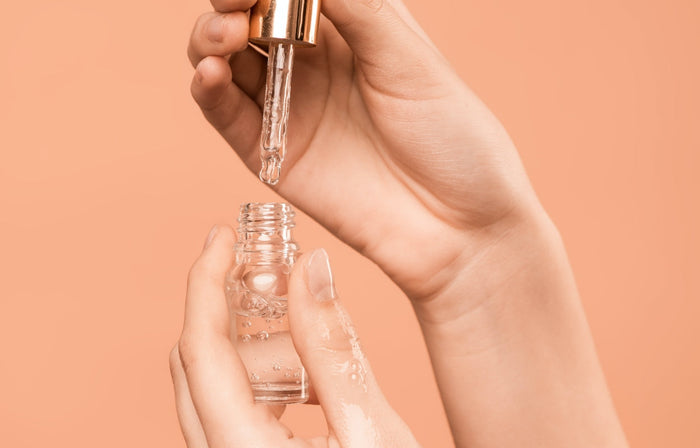 A lady holding a serum bottle and dropper