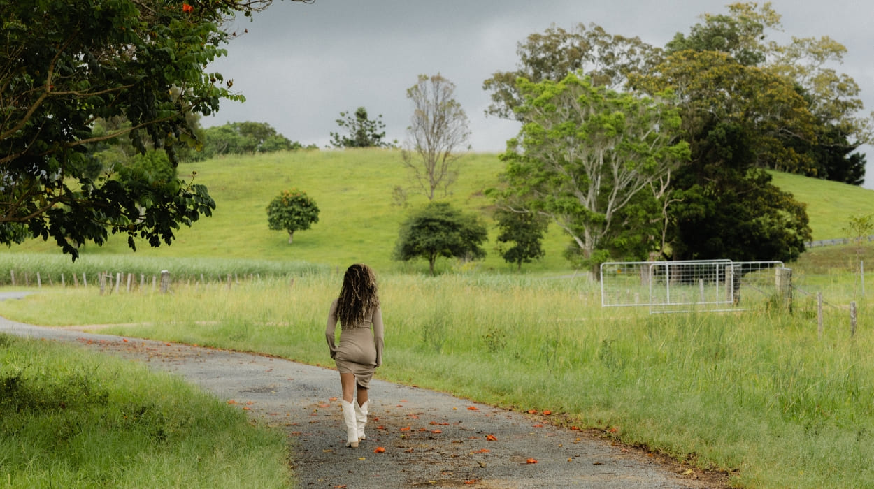 A woman walks on a path through a farm