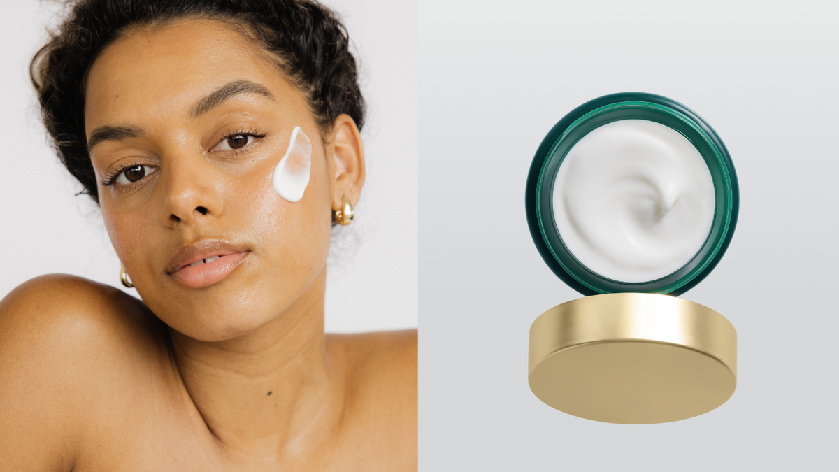 Woman applying cream to her face with a jar of cream on a white background