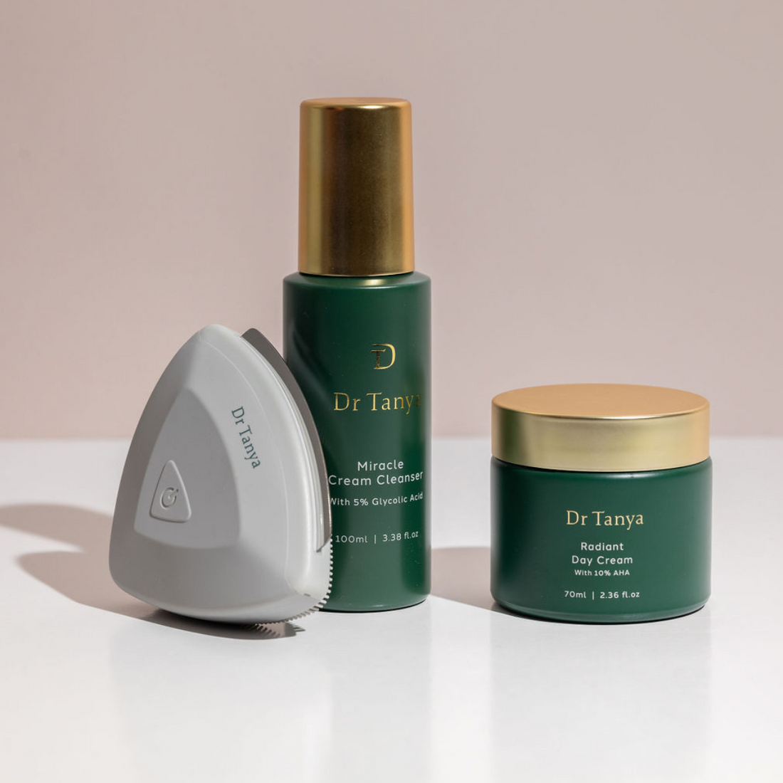 A Dr Tanya Nusonic exfoliator propped against a green bottle of cleanser and a green pot of facial cream