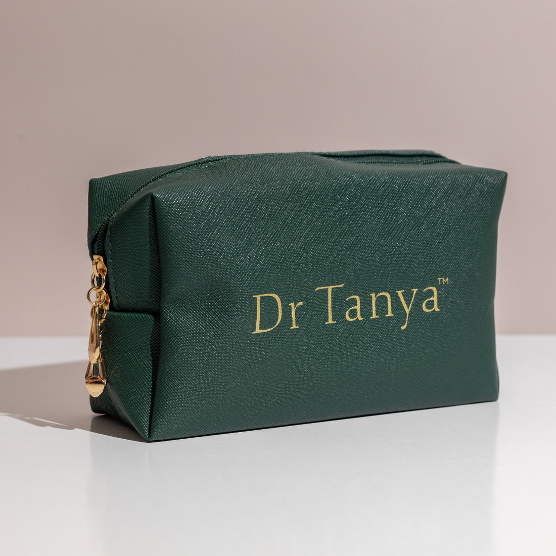 An emerald green toiletries bag with gold text saying Dr Tanya printed on the front