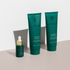 Three emerald bottles of hair care products lined up at an angle