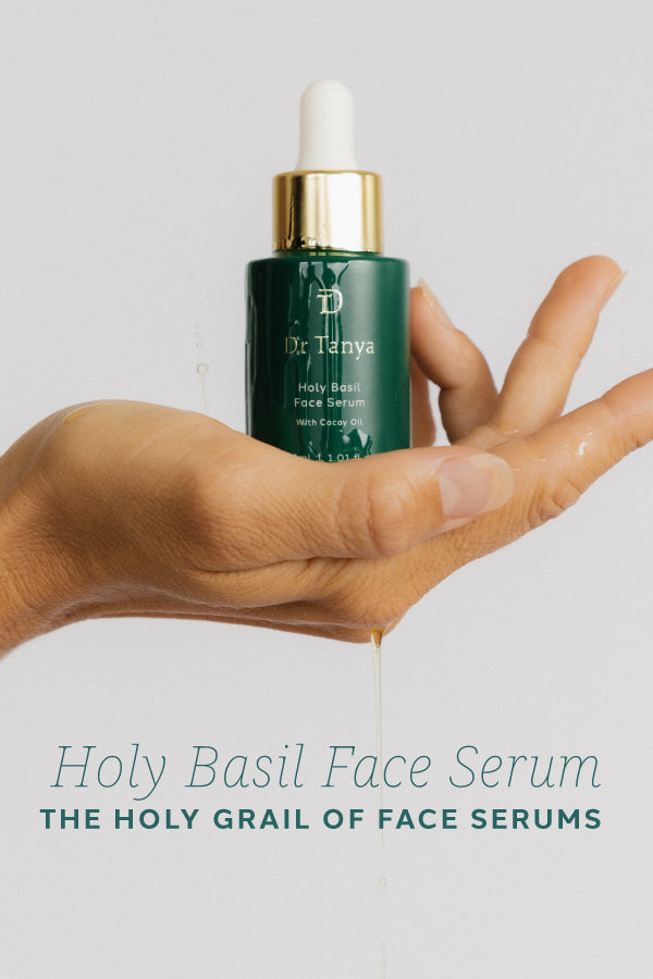 A bottle of face serum in the palm of a woman's hand