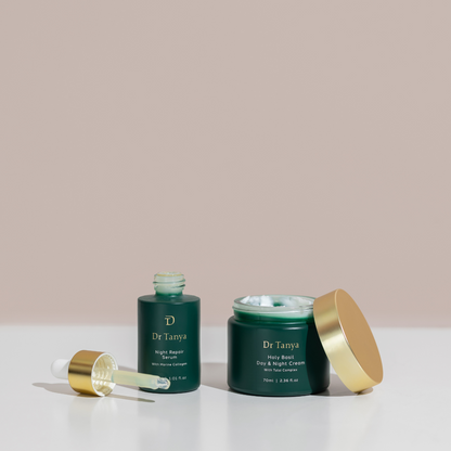 Two deep green bottles of face product with their gold lids off set against a pale pink background