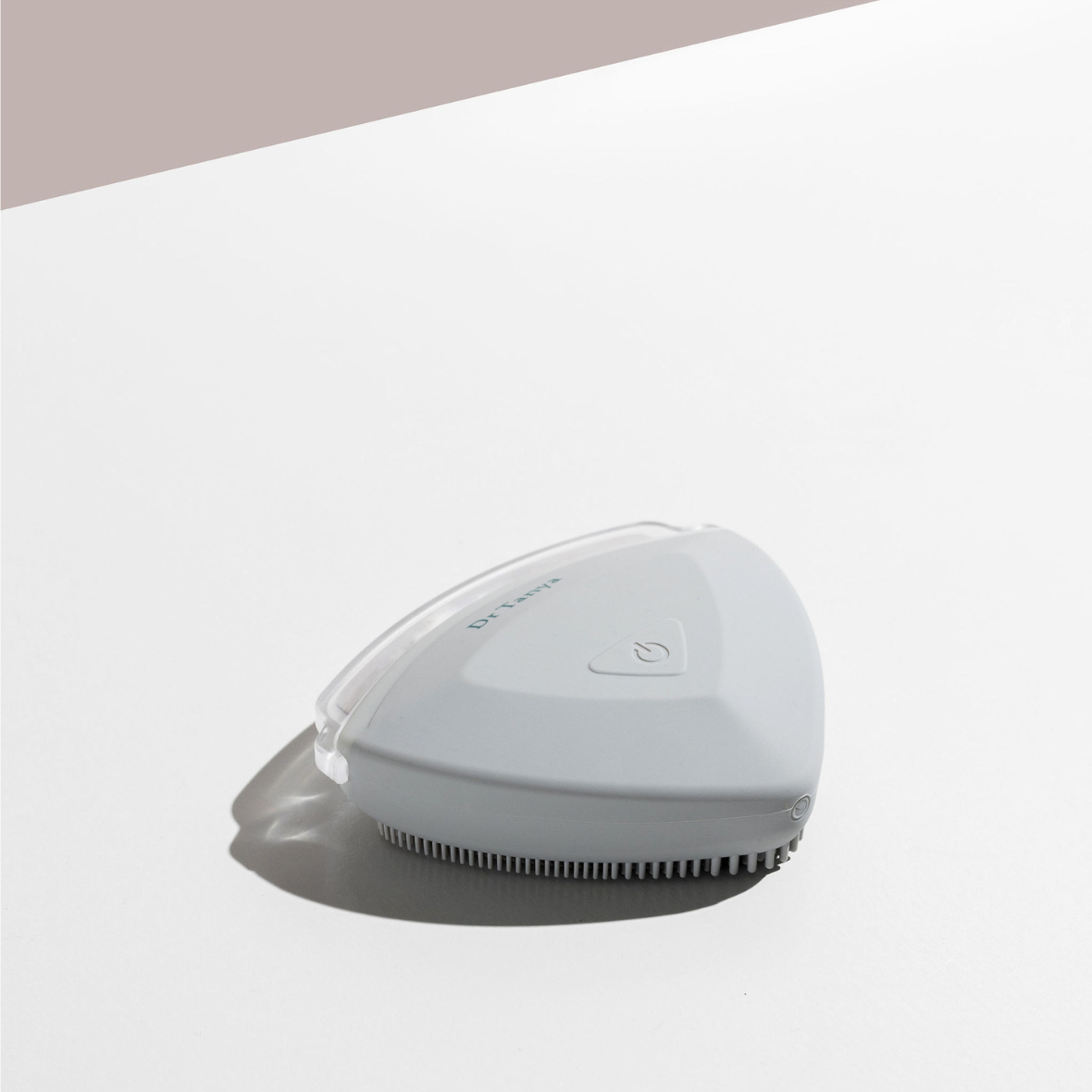 A white facial exfoliating device with a power button and a clear lid on top