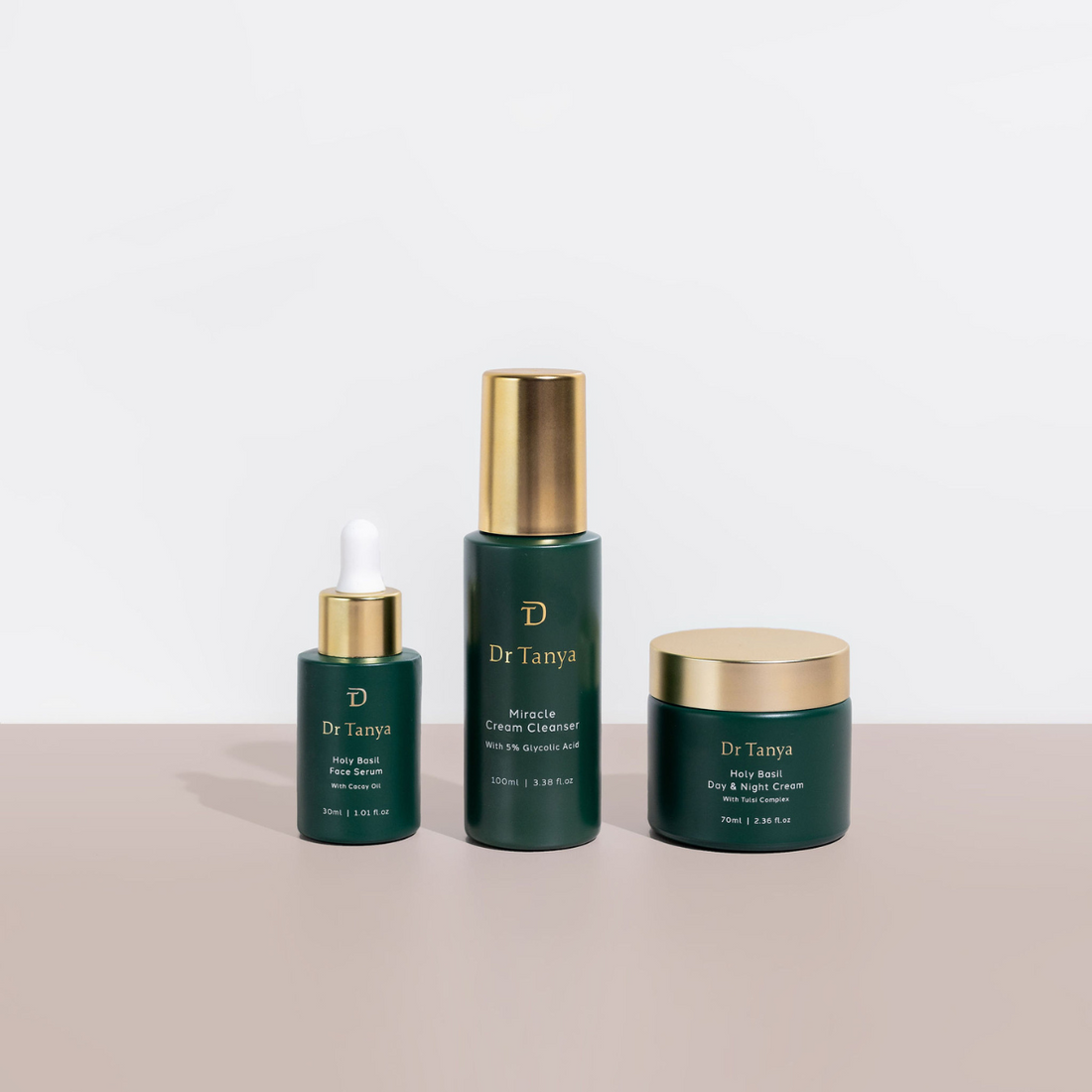 Three green bottles of skin products with gold lids