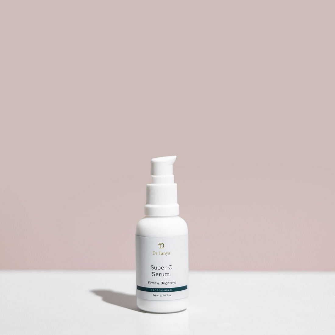 A single white bottle of vitamin c face serum in front of a pink wall